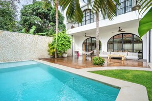 Uma casa moderna com piscina, deck de madeira e área de estar ao ar livre.