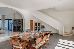 A dining area with a long table set for a meal, surrounded by wooden chairs with woven seats. - Bianca Villa by Betterplace (Canggu)