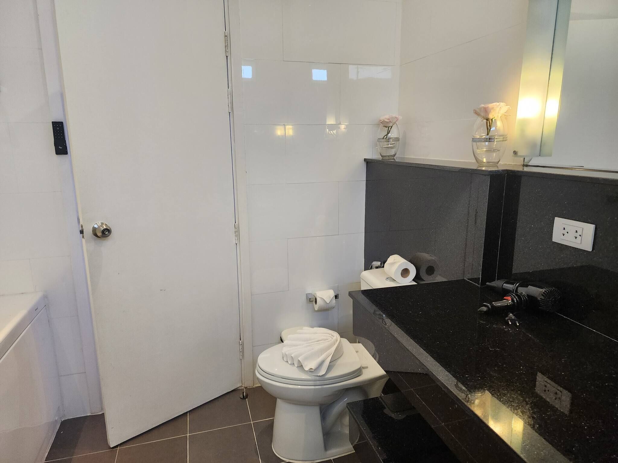 A bathroom with a toilet, a sink, a mirror, and a shower area.