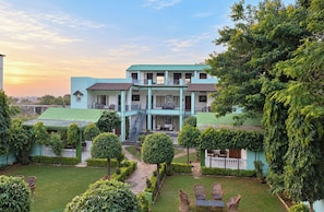 A two-story building with a central staircase, surrounded by a well-maintained garden with various shrubs and a lawn. - Ranthambhore Vatika Resort (Sawai Madhopur)