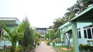 A pathway leading to a building with a green exterior and multiple windows. - Ranthambhore Vatika Resort (Sawai Madhopur)