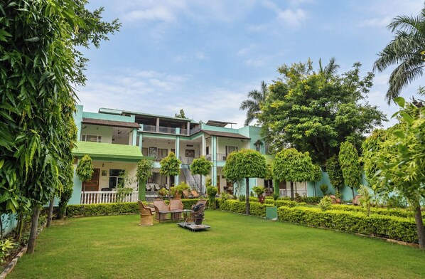 A hotel with a green lawn, outdoor seating, and a two-story building.