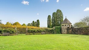 A grassy field with a stone structure and a bench. - 2 bedroom accommodation in Sturminster Newton (Sturminster Newton)