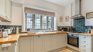 A modern kitchen with a large window, a built-in microwave, and a stainless steel range hood. - 2 bedroom accommodation in Sturminster Newton (Sturminster Newton)