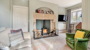 A living room with a fireplace, a green sofa, a beige sofa, and a television mounted on the wall. - 2 bedroom accommodation in Sturminster Newton (Sturminster Newton)