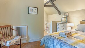 A bedroom with a bed, a chair, a dresser, and a radiator. - 1 bedroom accommodation in Sturminster Newton (Sturminster Newton)