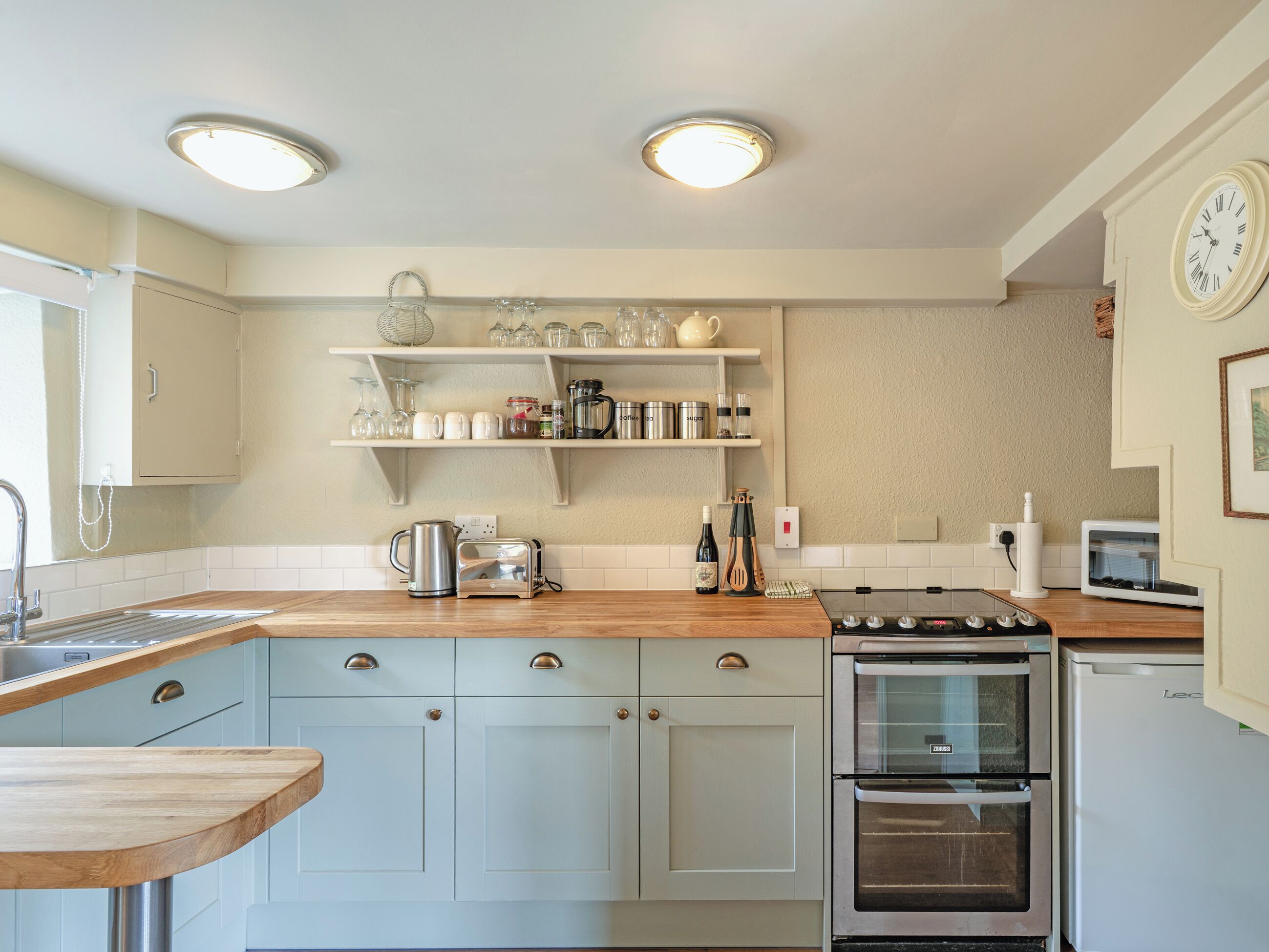 A kitchen with a wooden countertop, stainless steel appliances, and white cabinetry.