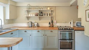 A kitchen with a wooden countertop, stainless steel appliances, and white cabinetry. - 1 bedroom accommodation in Sturminster Newton (Sturminster Newton)