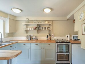 Una cocina con encimera de madera, electrodomésticos de acero inoxidable y armarios blancos.