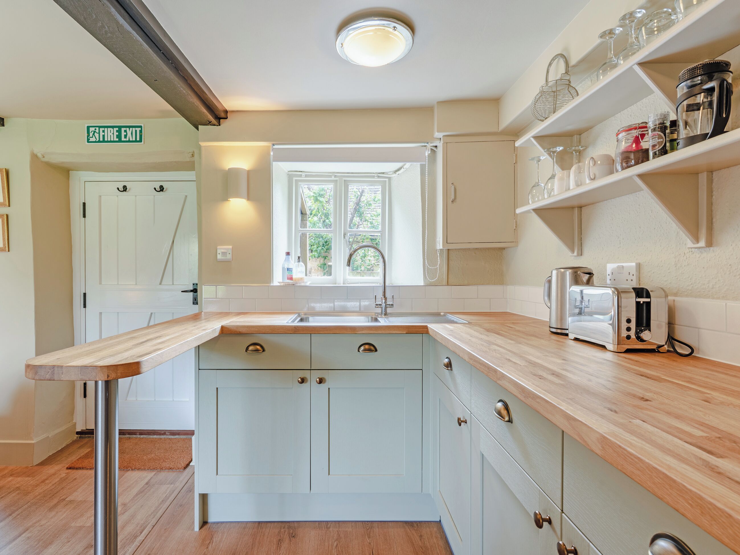 A kitchen with a central island, a sink, and a window with a view of greenery.