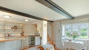 A cozy kitchen with a dining area, a brown leather sofa, and a view through a window. - 1 bedroom accommodation in Sturminster Newton (Sturminster Newton)