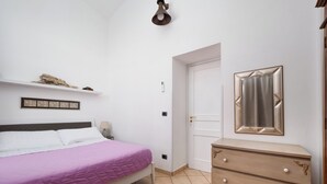 Ein Schlafzimmer mit einem Bett, einem Schminktisch, einer Tür und einer Wandleuchte.