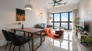 A modern living room with a dining area, large windows, a ceiling fan, and a TV. - KLCC Agile Bukit Bintang---5 mins to TRX (Kuala Lumpur)