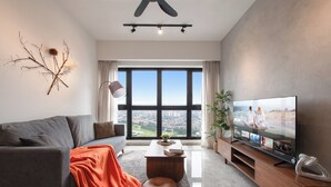 A modern living room with a grey sofa, a coffee table, and a flat-screen TV on a wooden stand. - KLCC Agile Bukit Bintang---5 mins to TRX (Kuala Lumpur)