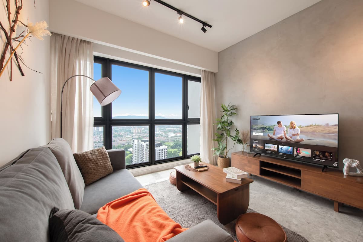 A modern living room with a large window, a flat-screen TV, a sofa, a coffee table, and a potted plant.