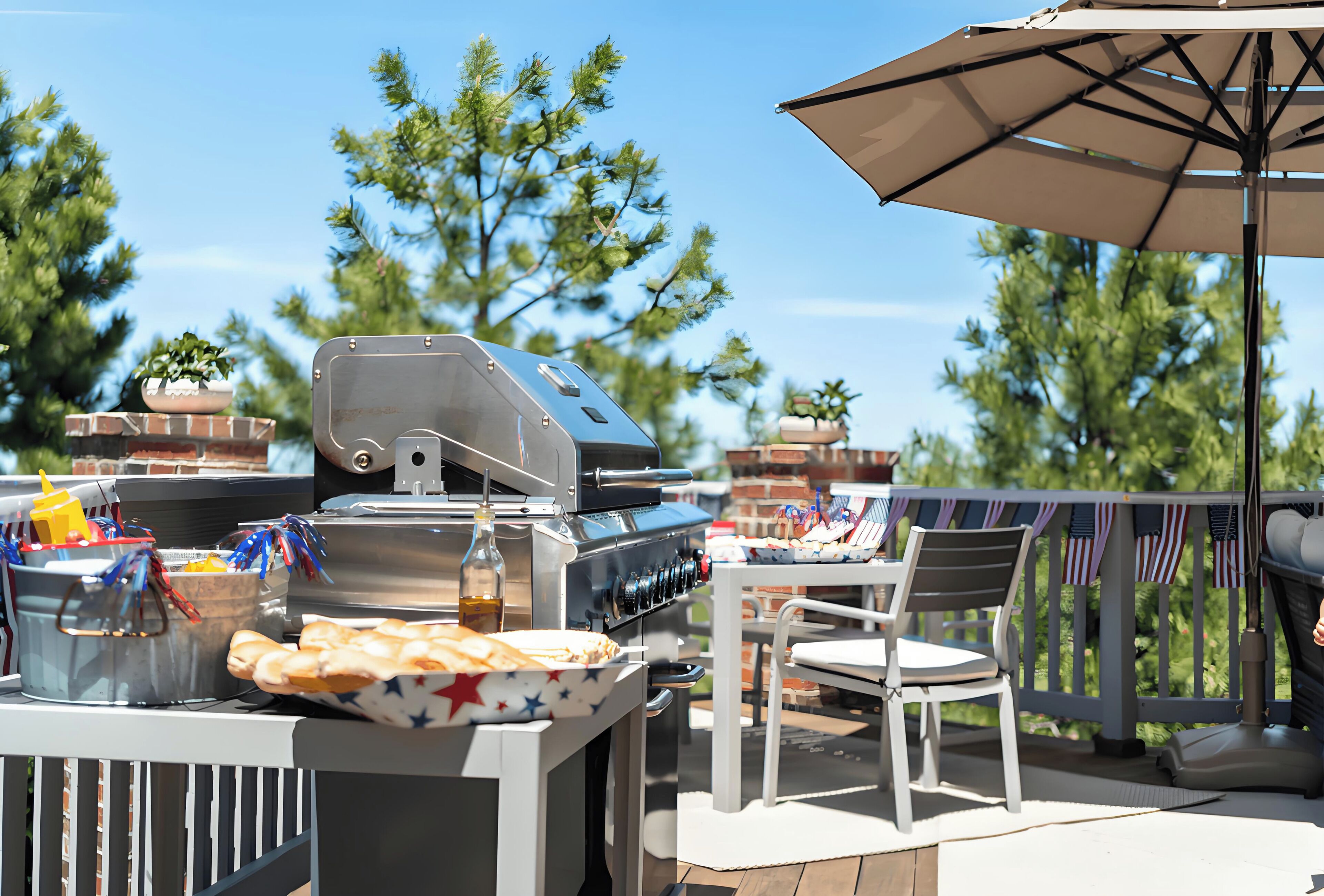An outdoor barbecue setup with a grill, a table with chairs, and a decorative umbrella.