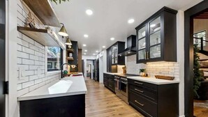 Una cucina moderna con isola centrale, mobili scuri e pannello di rivestimento bianco.