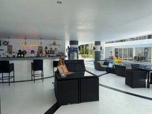 Eine moderne Bar mit Neonreklame, Sitzgelegenheiten am Pool und einem Schild, das die Happy Hour anzeigt.