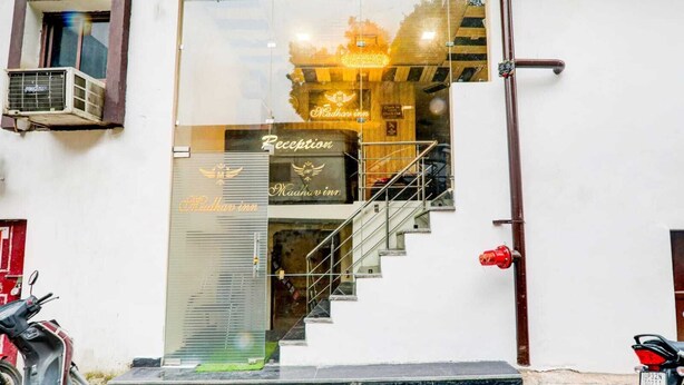 A hotel entrance with a reception desk, a staircase, and a parked motorcycle. - Madhav Inn Lucknow (Lucknow)