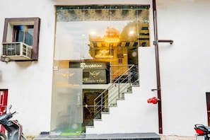 A hotel entrance with a reception desk, a staircase, and a parked motorcycle. - Madhav Inn Lucknow (Lucknow)