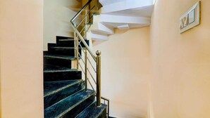 A staircase with black marble steps and a metal railing, leading to a landing with a white wall and a framed picture. - Madhav Inn Lucknow (Lucknow)