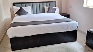 A bed with a headboard, a bedside table, and a window. - Madhav Inn Lucknow (Lucknow)