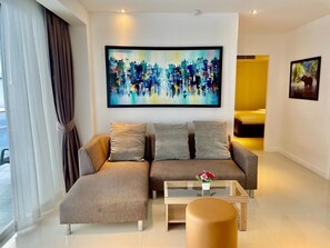 Ein modernes Wohnzimmer mit einem Ecksofa, einem Glastisch und einem Bild an der Wand.