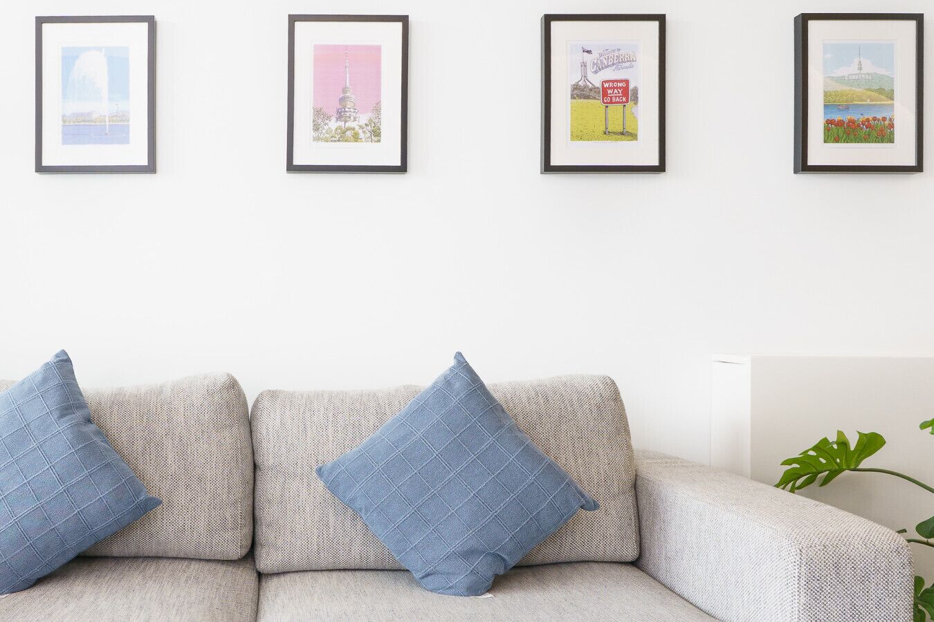 Un salon avec un canapé et trois œuvres d’art encadrées accrochées au mur.