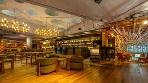 Una amplia biblioteca con pisos de madera, varias zonas de estar y un bar con estanterías llenas de libros y botellas.