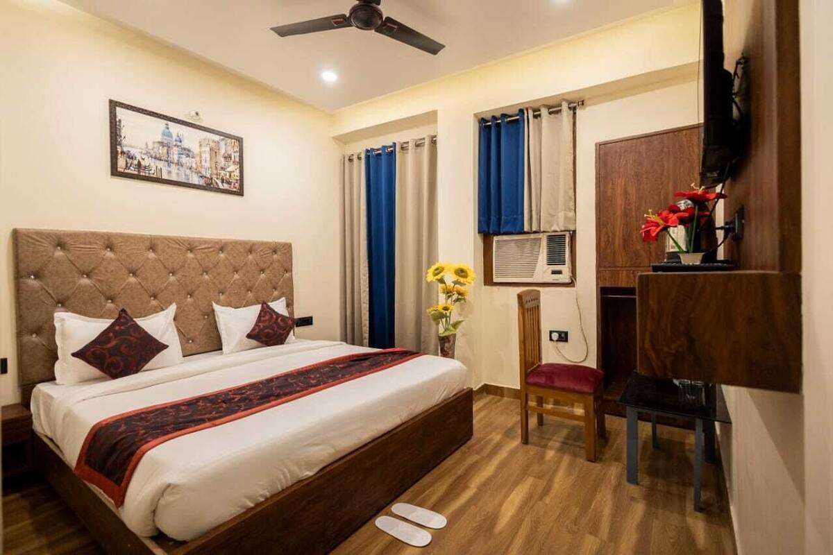 A hotel room with a large bed, a ceiling fan, a TV, a desk, and a chair.
