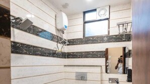Un baño con lavamanos, inodoro y ducha blancos. Hay una ventana sobre el lavamanos y un espejo en la pared.