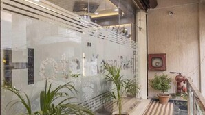 Un interior moderno con pared de vidrio, plantas en macetas y techo de madera.