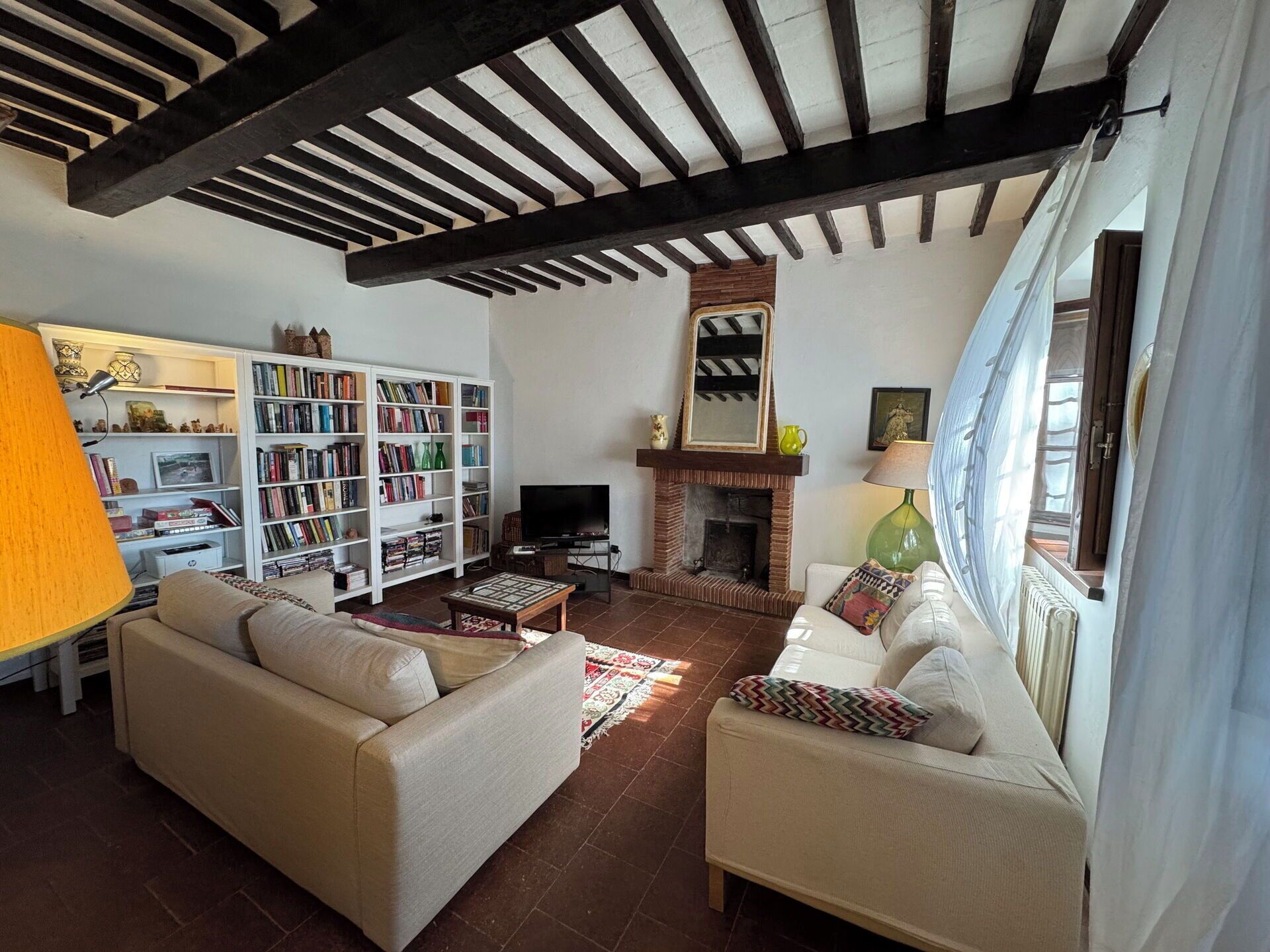 Ein Wohnzimmer mit Kamin, Bücherregalen, Sofas und einem Fernseher.