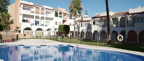 Un hôtel doté d’une piscine, de plusieurs balcons et de palmiers.
