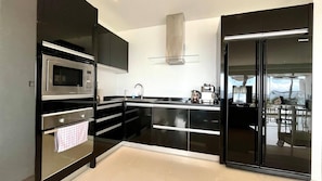Eine moderne Küche mit schwarzen Schränken, Edelstahlgeräten und einem großen Kühlschrank.