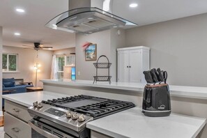 A modern kitchen with a gas stove, a range hood, and a knife block. - Hill House- Centrally Located, close to everything (Pensacola)