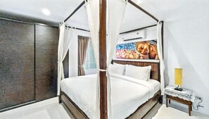Ein Himmelsbett mit Baldachin, ein Nachttisch mit Lampe und eine Wand-Klimaanlage.