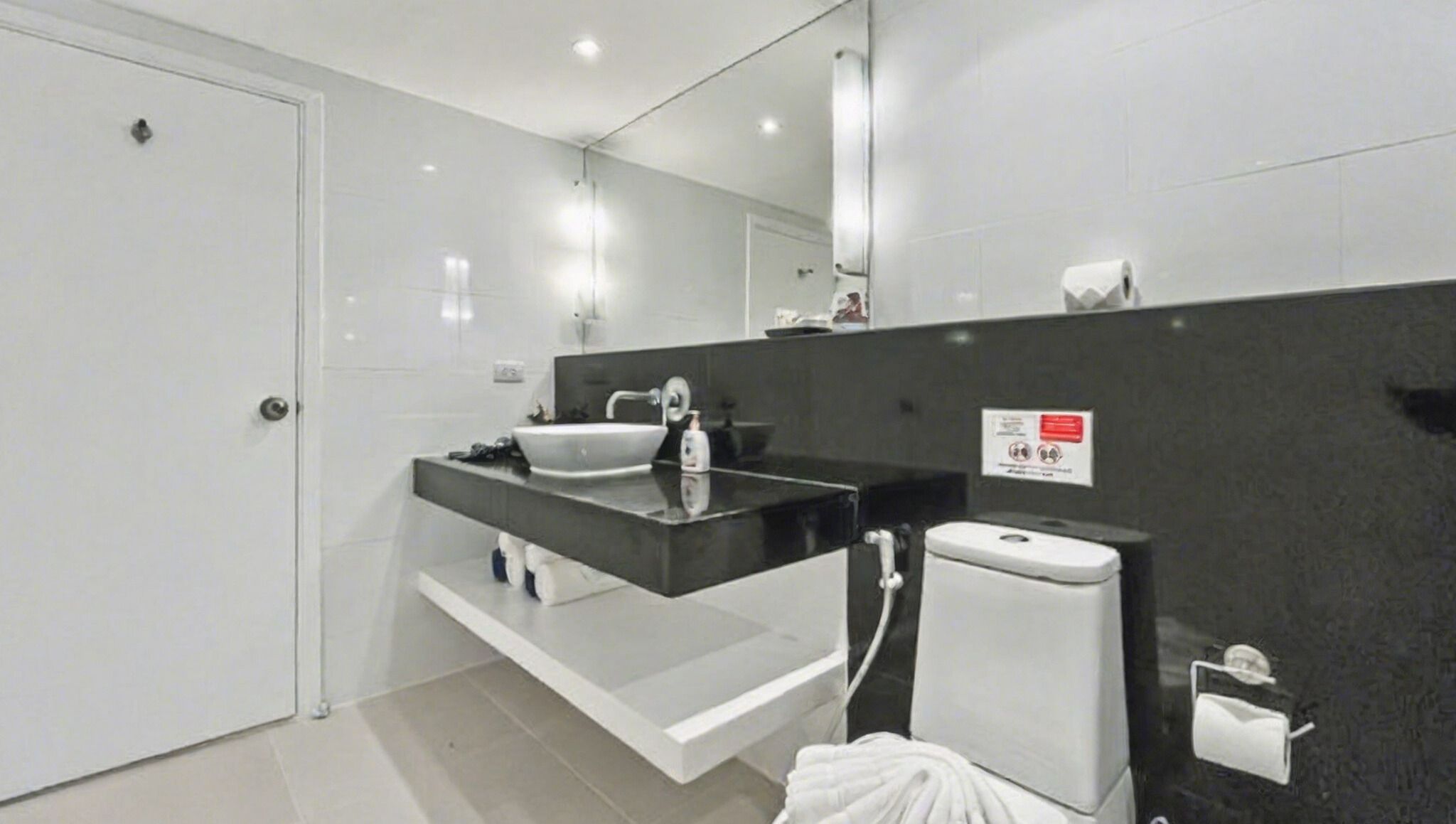 A modern bathroom with a white sink, dark countertop, and a toilet.