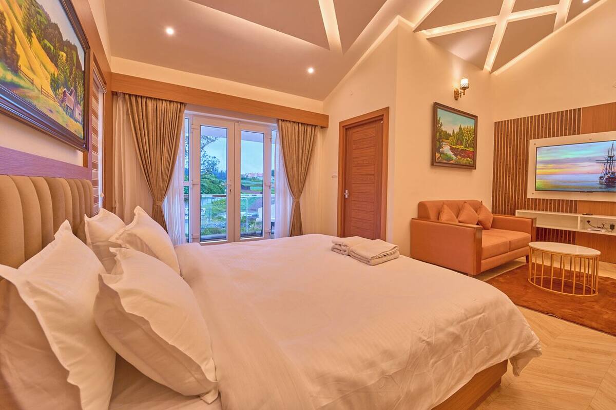 Ein geräumiges Schlafzimmer mit einem großen Bett, einer Couch, einem Fernseher und Blick ins Freie.