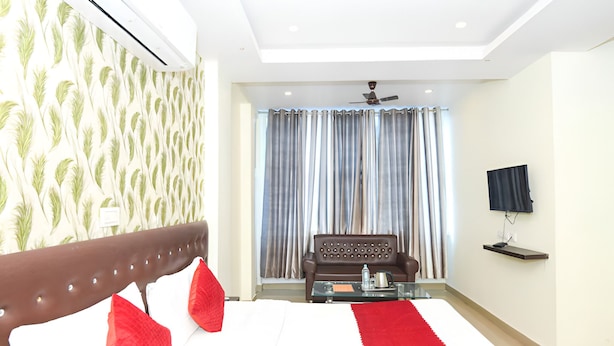 A modern hotel room with a large bed, a sofa, a TV, and a ceiling fan. - Hotel Moon Light Kanpur (Lucknow)