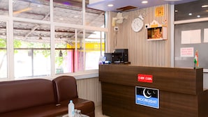 A reception area with a wooden desk, a brown leather couch, and a glass table with amenities. - Hotel Moon Light Kanpur (Lucknow)