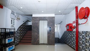 A lobby with a staircase, a fire hose reel, and a wall-mounted electrical panel. - Hotel Moon Light Kanpur (Lucknow)