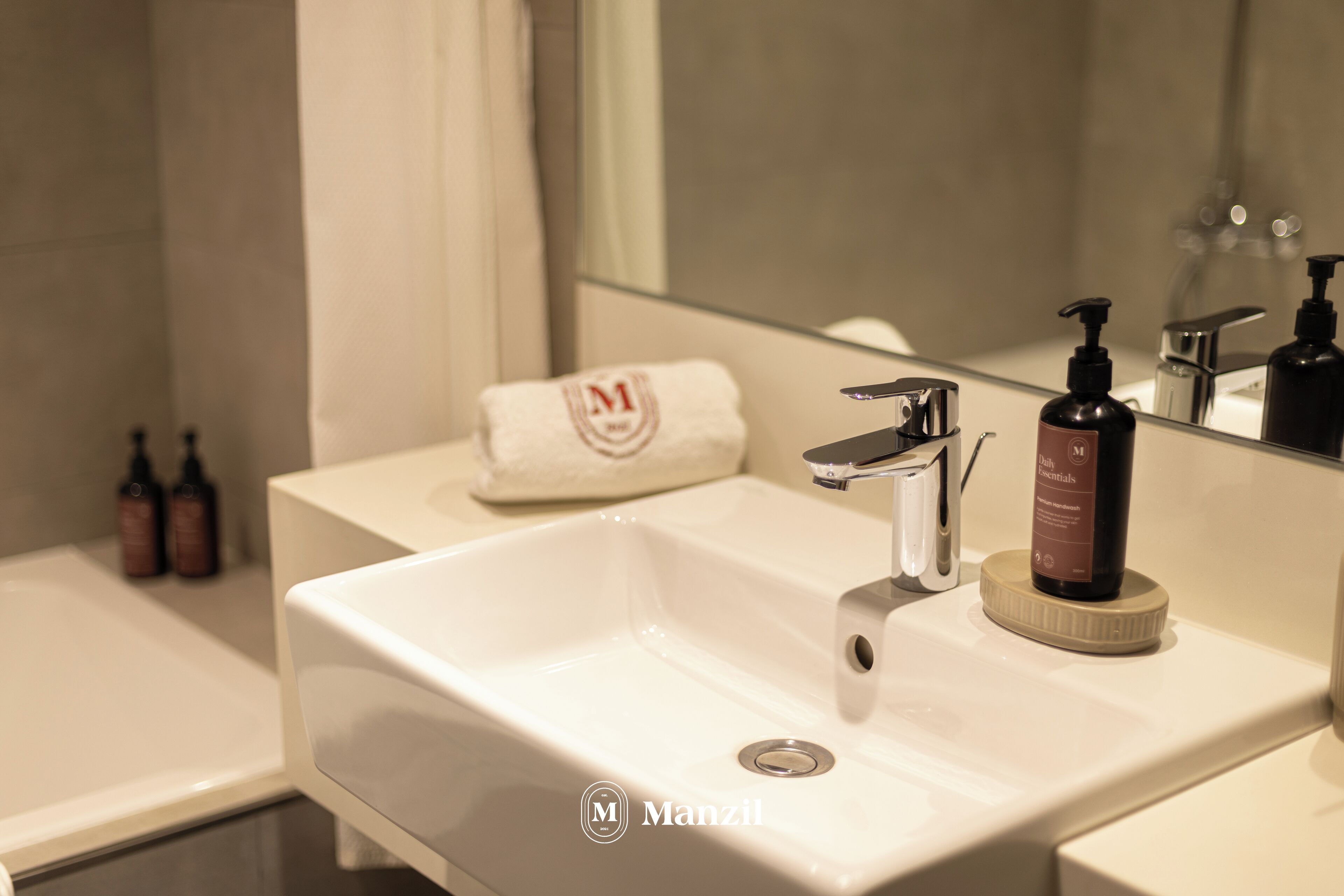 A bathroom with a white sink, a mirror, and a towel with a logo.
