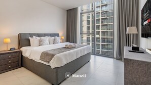 A modern hotel room with a large bed, a desk, and a large window with curtains.