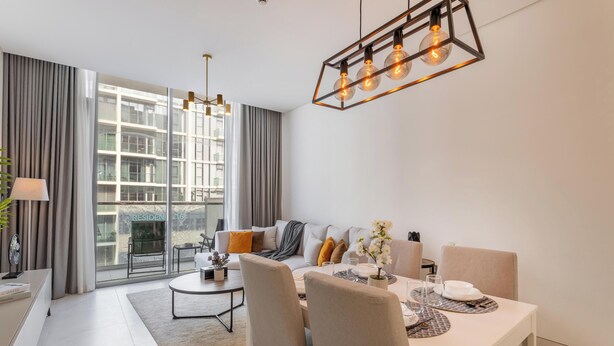 A modern living room with a dining area, large windows, and a view of a building.