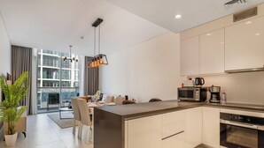 A modern kitchen with a central island, a dining area with a table and chairs, and a large window providing natural light.