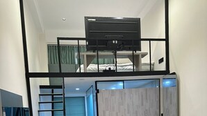 Una stanza moderna e funzionale con letto a soppalco, scrivania e divano.