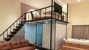 Un interno moderno con un divano, una scala, una vasca idromassaggio e una TV.