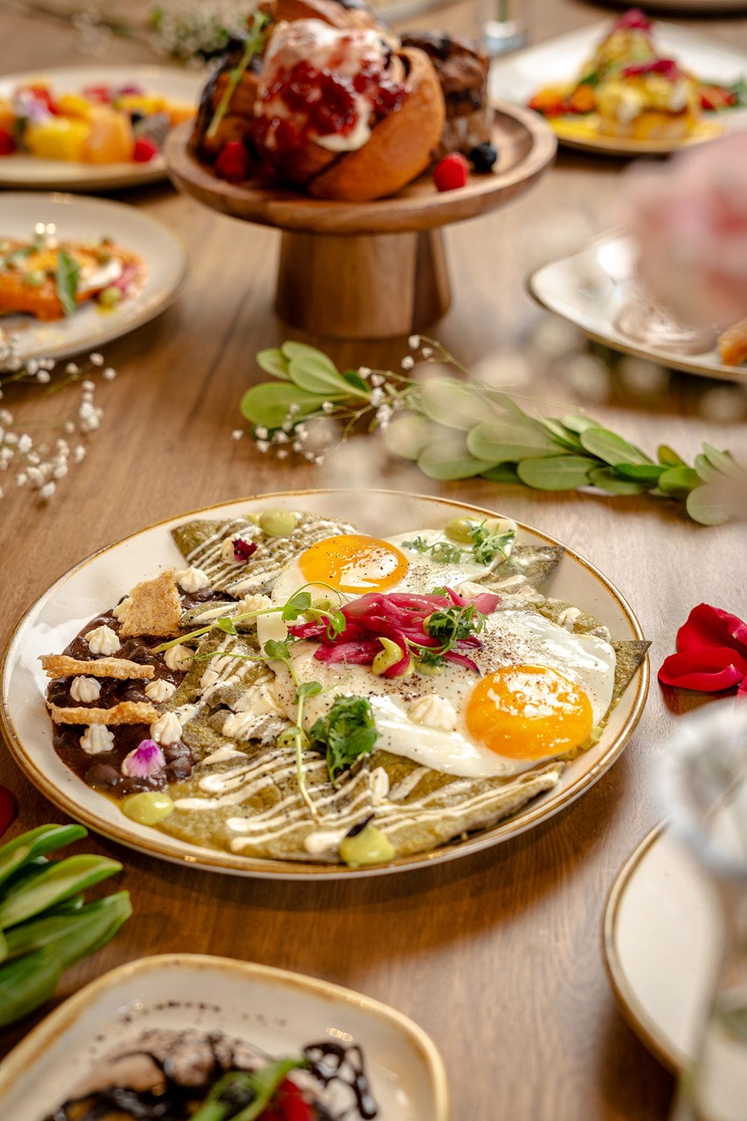 Una mesa de comedor con diferentes platos, incluyendo un plato con huevos, frijoles y vegetales.