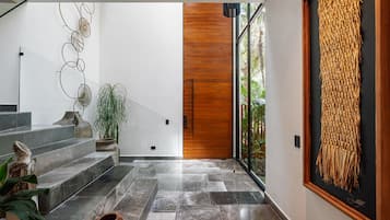 Un interior moderno con una escalera, una puerta de madera y una obra de arte grande enmarcada.